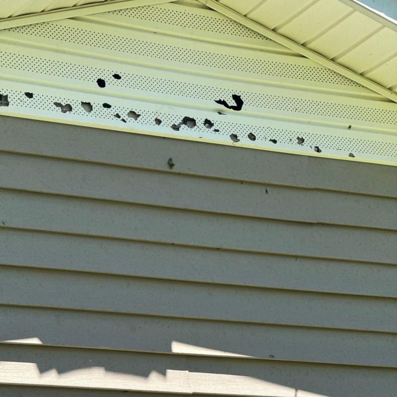 Eaves soffit perforated by hail damage on house exterior