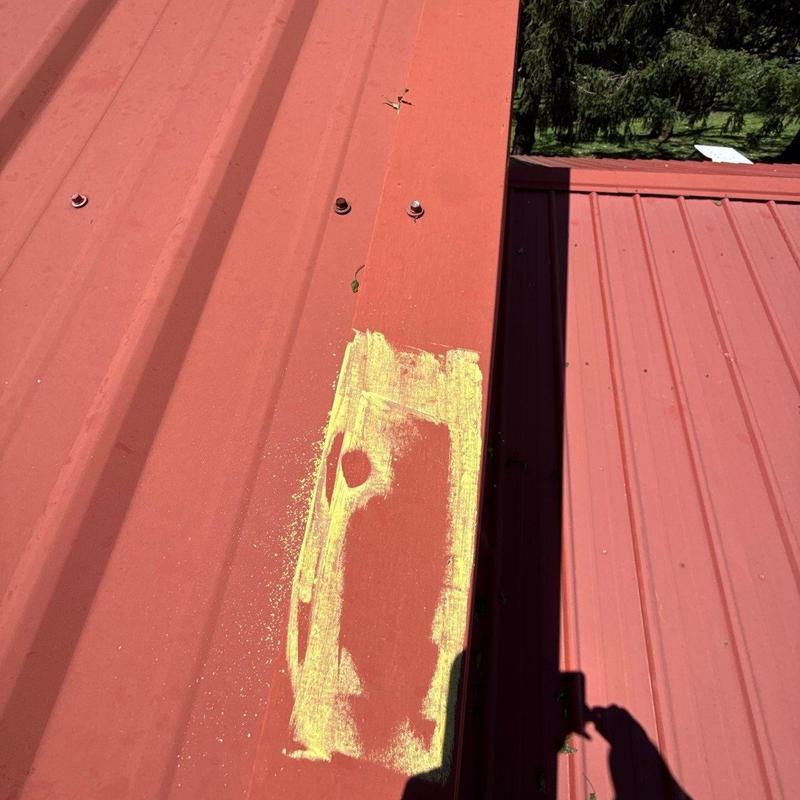Metal roof panel with hail damage marked in yellow