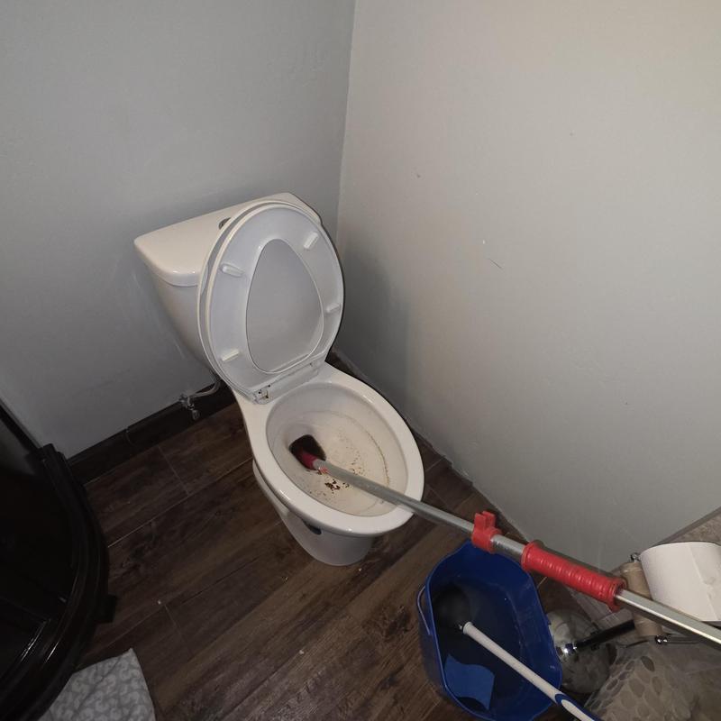 Toilet closet auger clearing blockage in bathroom