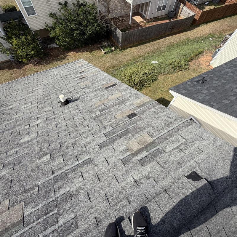 Roof shingles with missing and damaged areas on residential roof