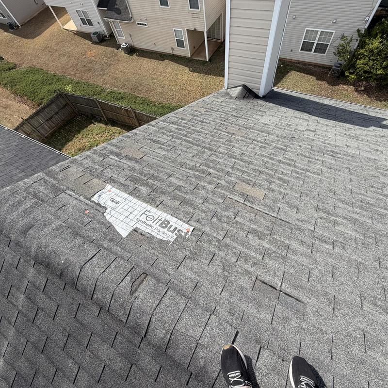Roof shingles with damaged and missing pieces near chimney