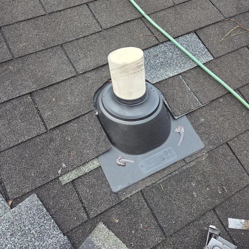 Roof pipe boot with surrounding shingles on asphalt roof