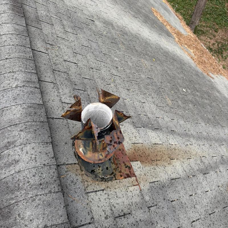 Rusty 5.5 rain cap on shingled roof before replacement