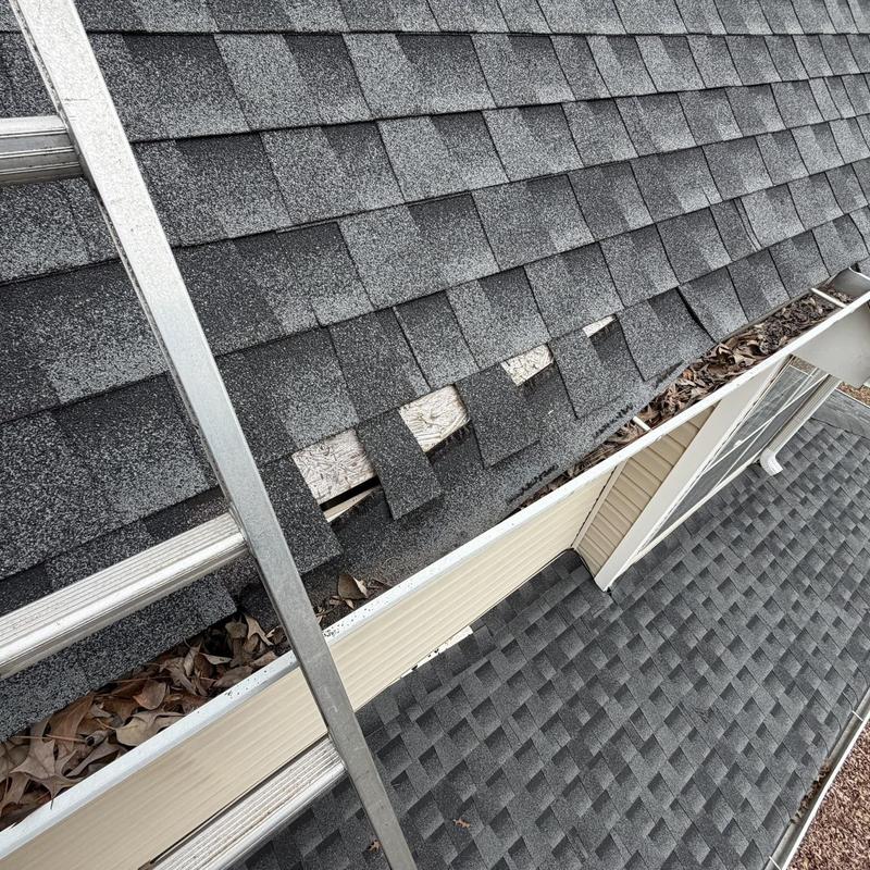 Asphalt roof shingles with visible damage near ladder