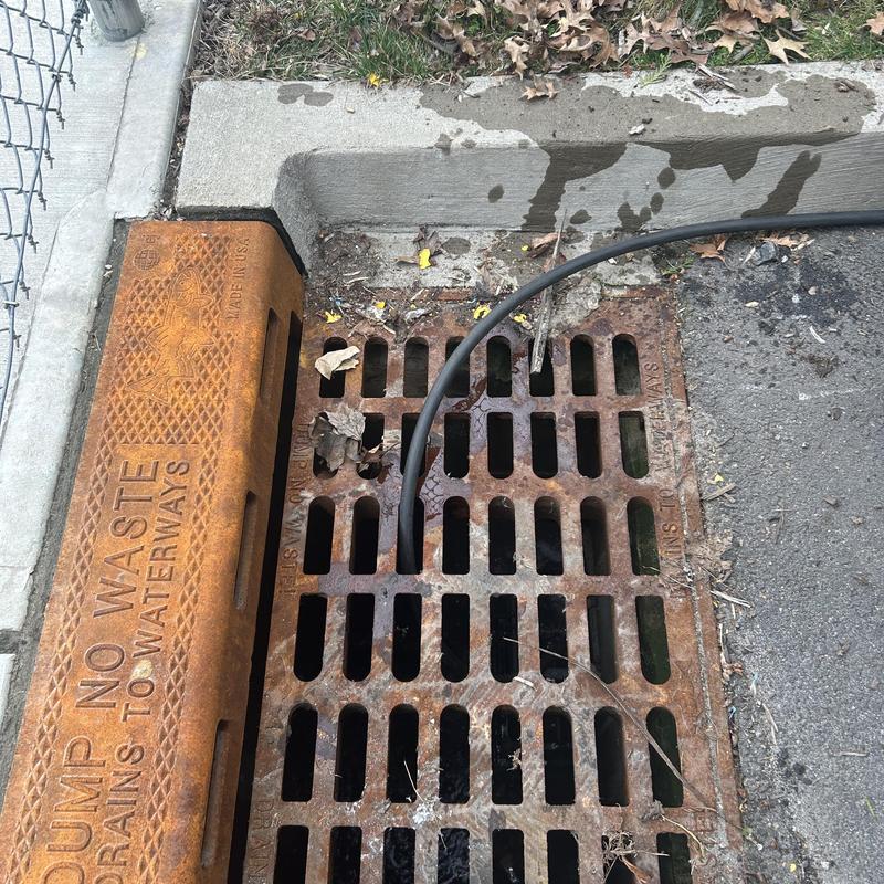 Storm drain jetting hose inserted into drain grate