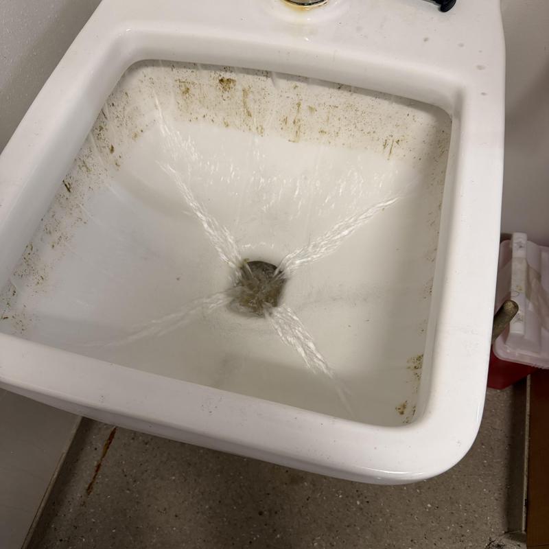 Utility sink drain with water flow testing in progress Utility sink drain with water flow testing in progress