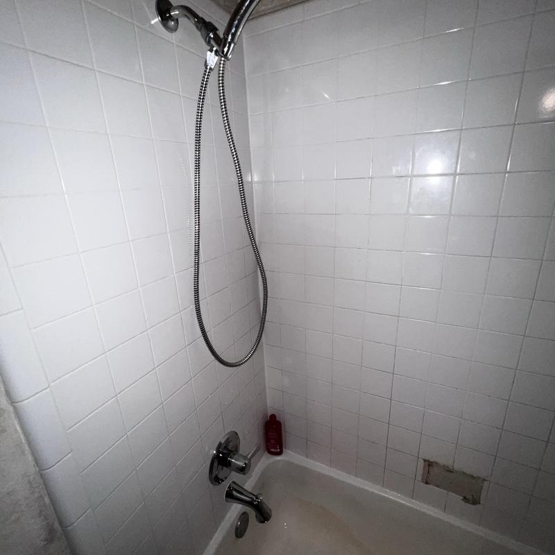Shower trim and tile wall in white bathroom