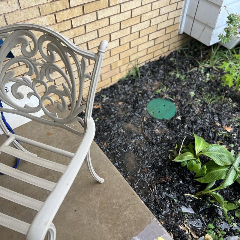 Pressure reducing valve cover in garden bed near porch