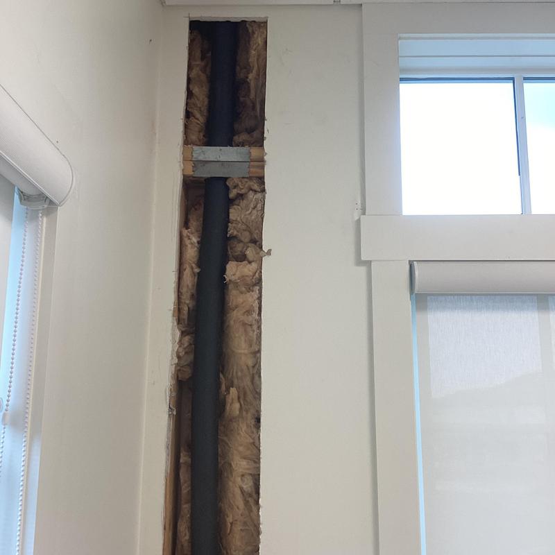 Insulated water pipe in wall cavity near window