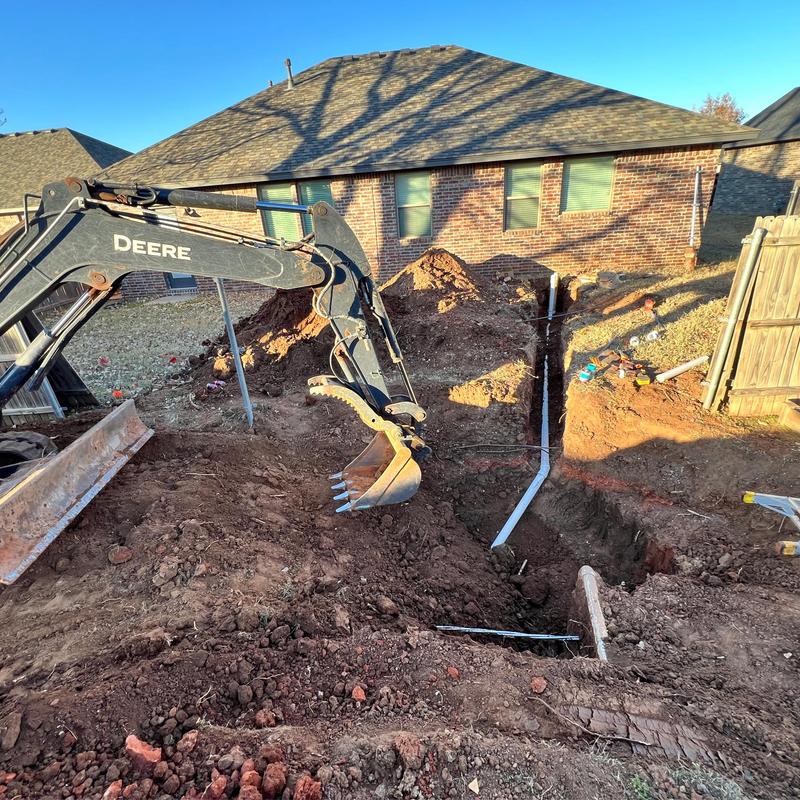 Sewer service line excavation with backhoe near house