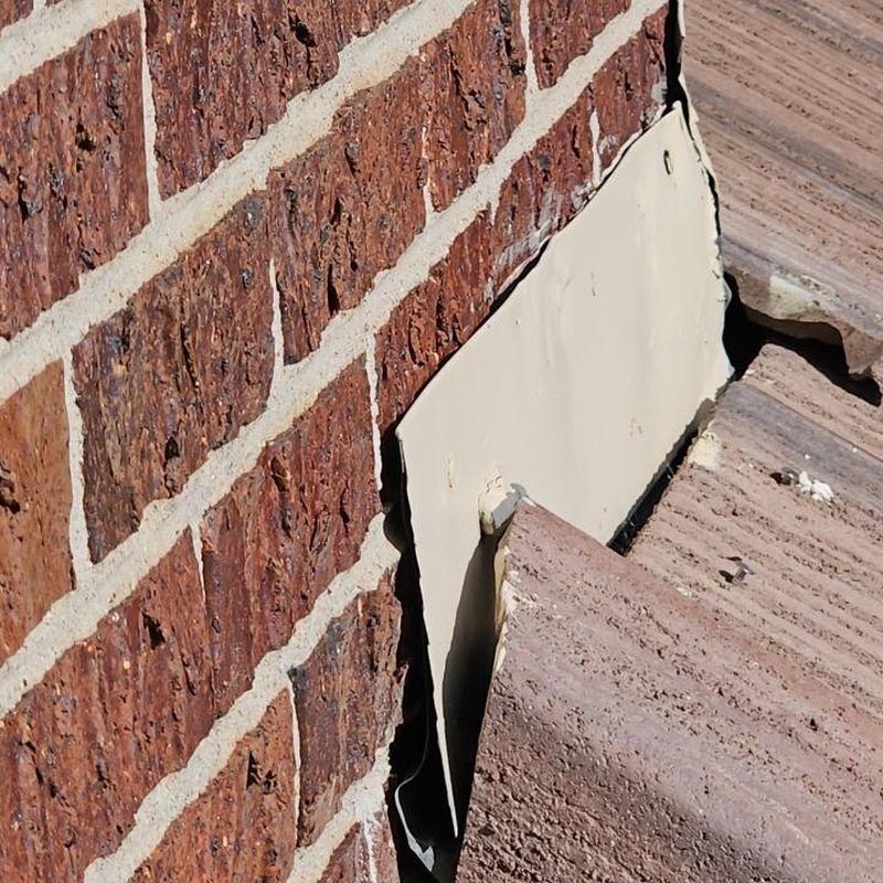 Tile roof flashing next to brick wall, gap visible Tile roof flashing next to brick wall, gap visible