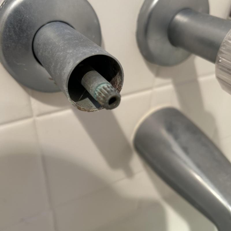 Shower valve stem with removed handle in bathroom wall