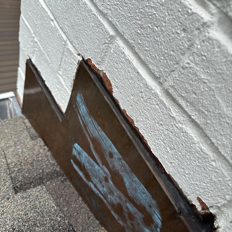 Roof flashing with rust damage along wall edge