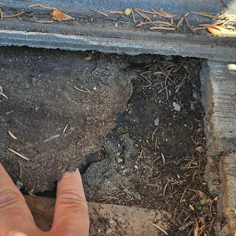 Asphalt driveway crack with soil exposed beneath Asphalt driveway crack with soil exposed beneath