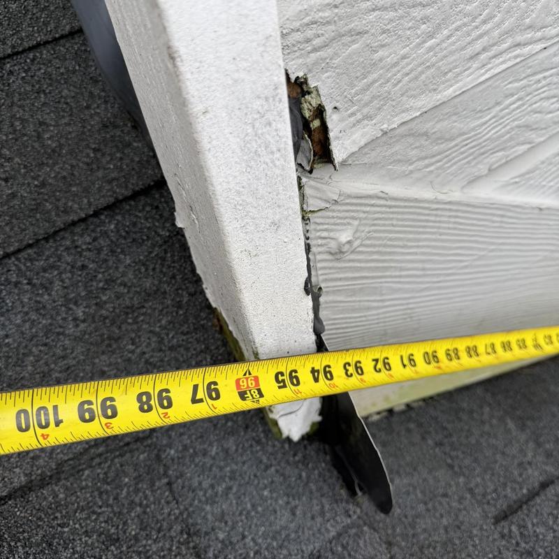 Chimney flashing gap with measuring tape on roof