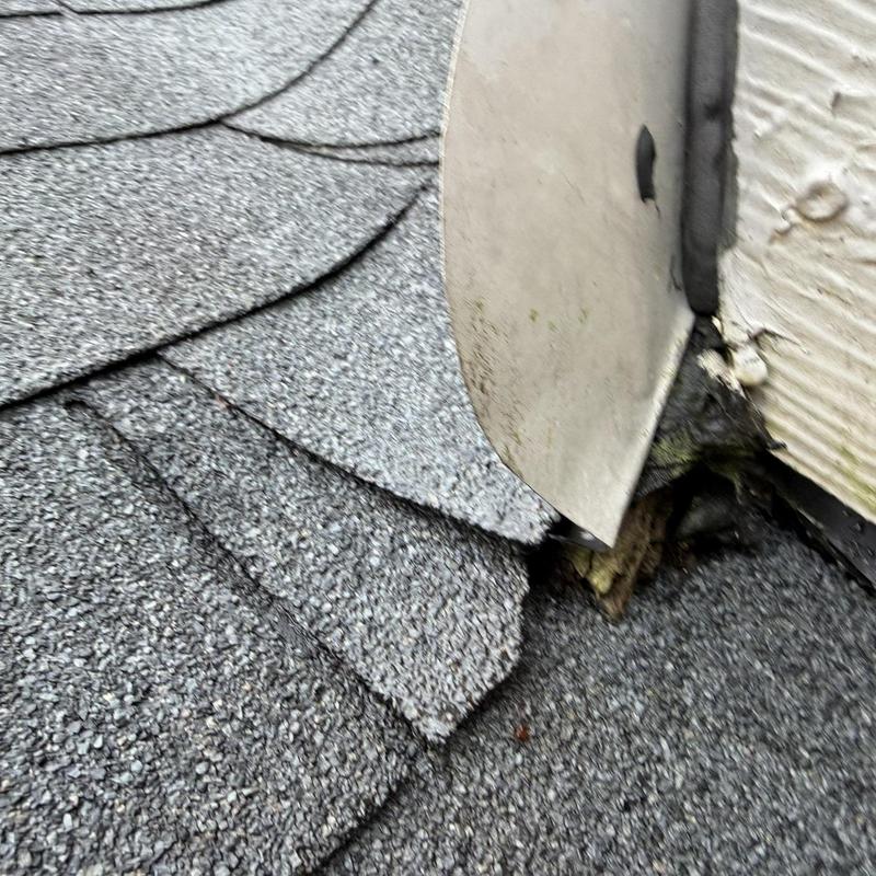 Chimney flashing with damaged roof shingles close-up