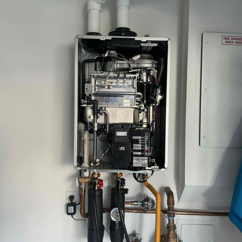 Tankless water heater with exposed piping and gauges