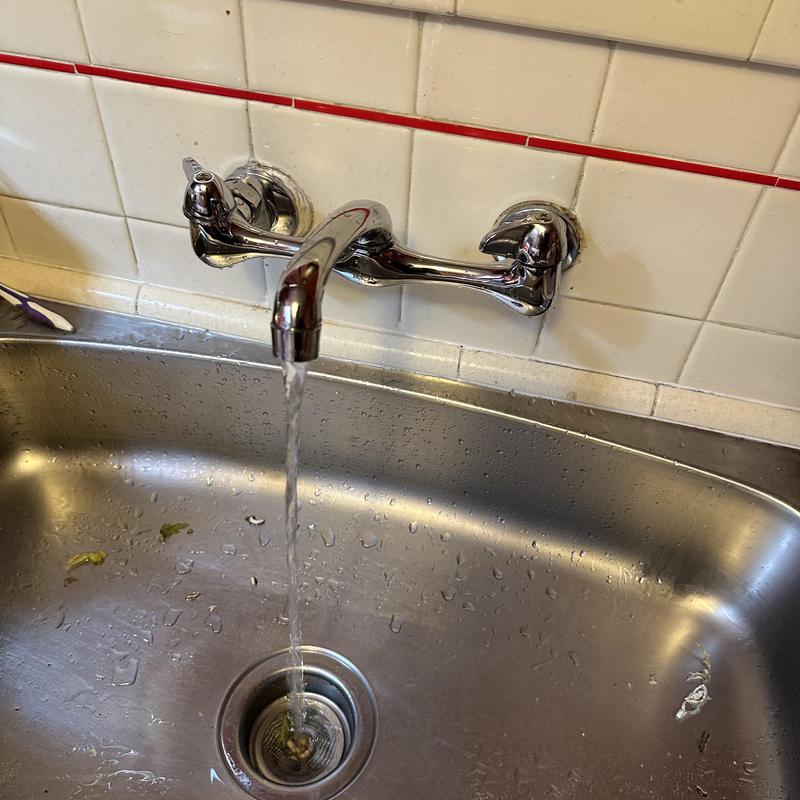 Wall-mounted kitchen faucet with water running