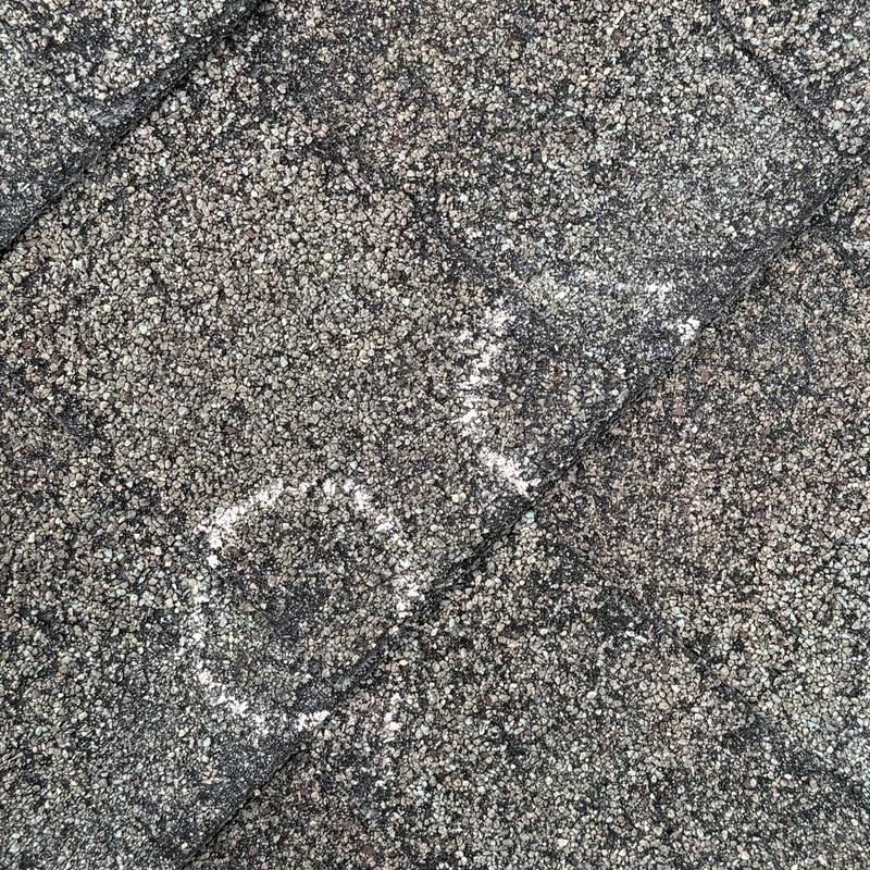 Asphalt shingle roof with chalk-marked damage areas