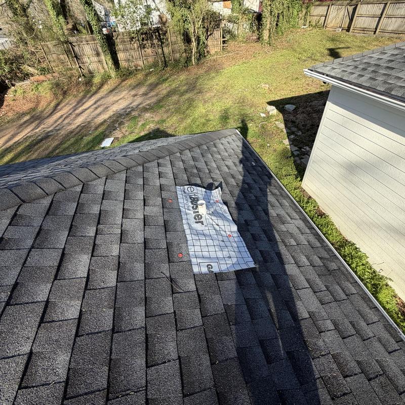 Roof shingles with protective tarp on charcoal shingle roof