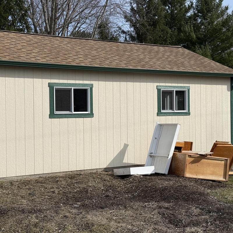 Shed exterior wall and windows with debris nearby