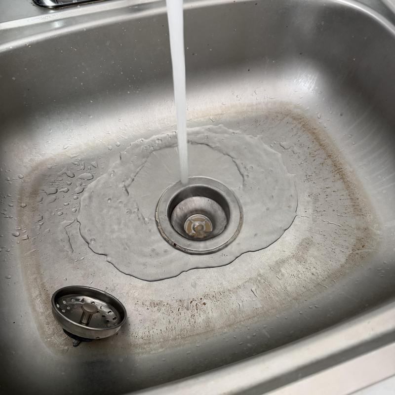 Kitchen sink drain with running water in stainless steel basin Kitchen sink drain with running water in stainless steel basin