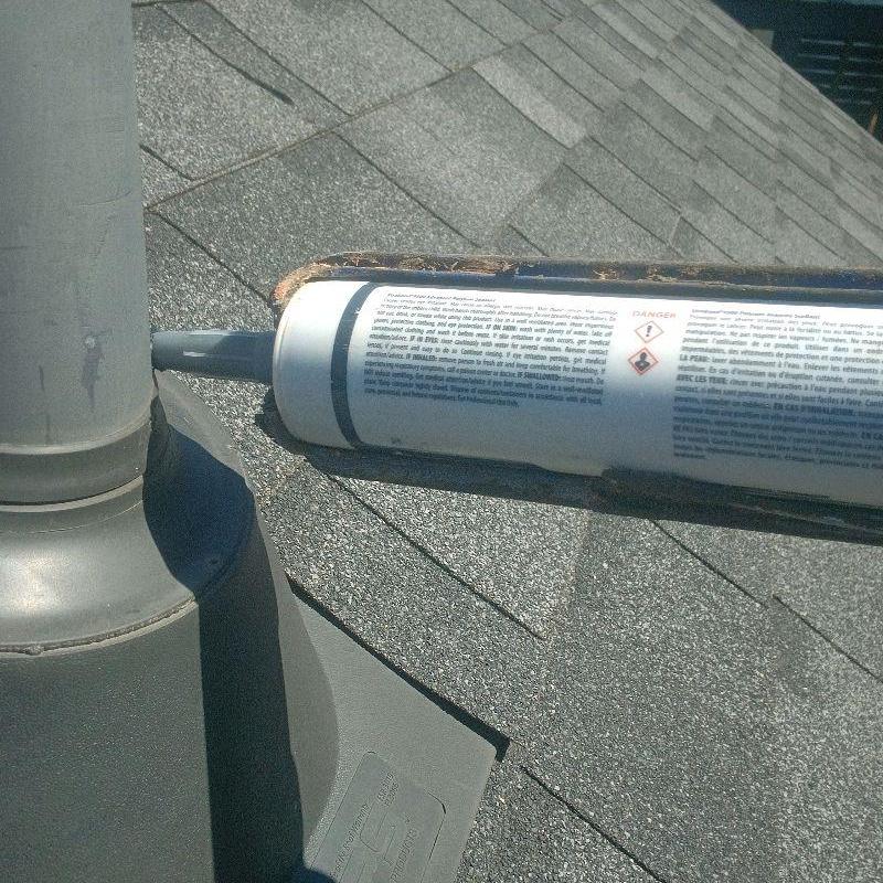 Pipe boot on roof being sealed with caulk tube