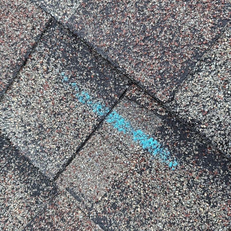 Asphalt shingles with marked hail damage on roof surface