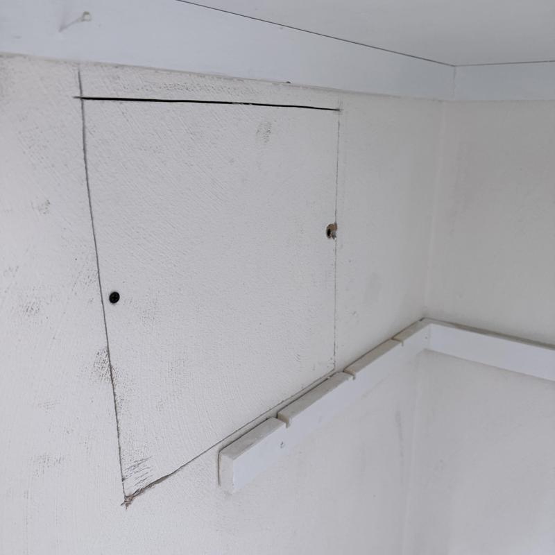 Shower valve access panel in white wall corner Shower valve access panel in white wall corner