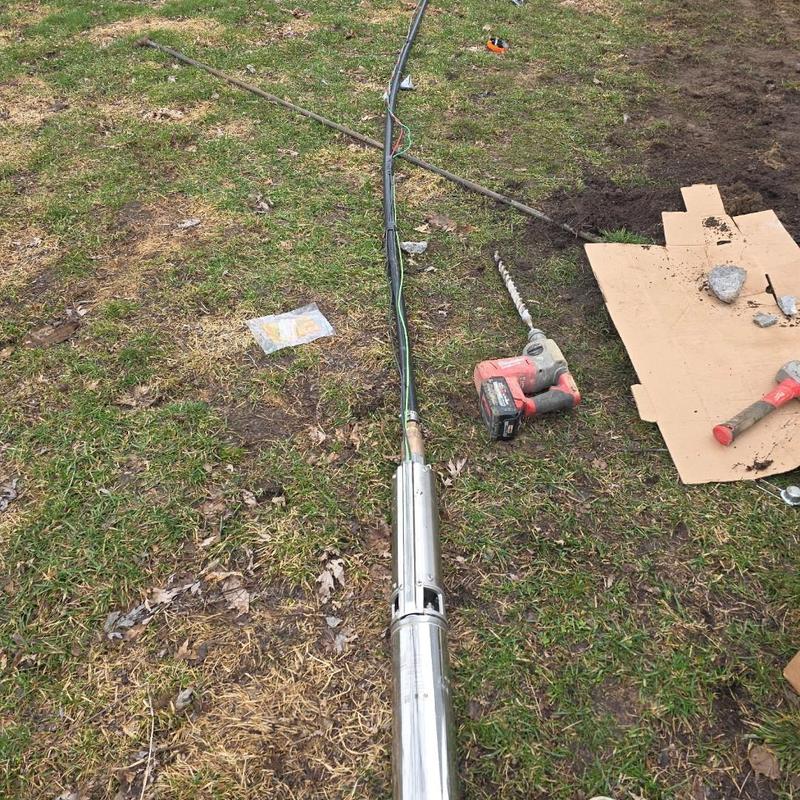 Deep well pump with electrical wiring and tools on grass