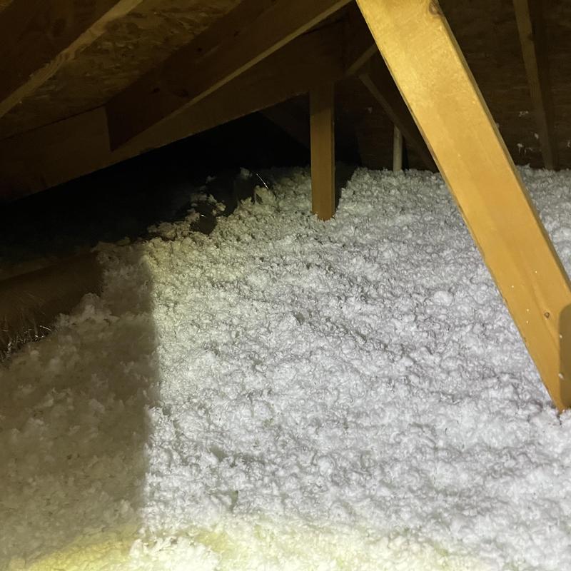 Attic loose-fill insulation installation in wooden frame attic