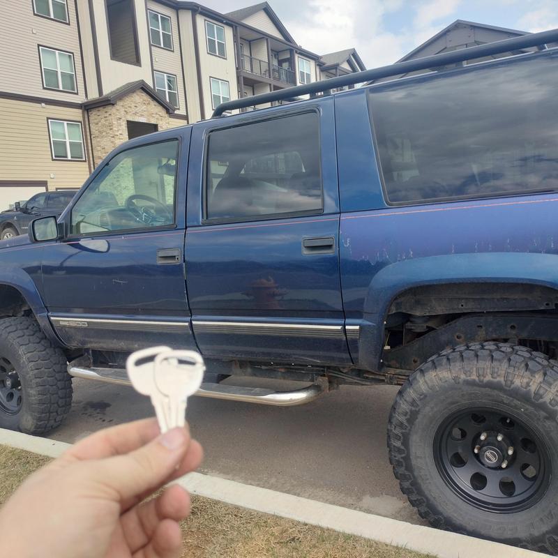 Vehicle key duplication with blue SUV in background