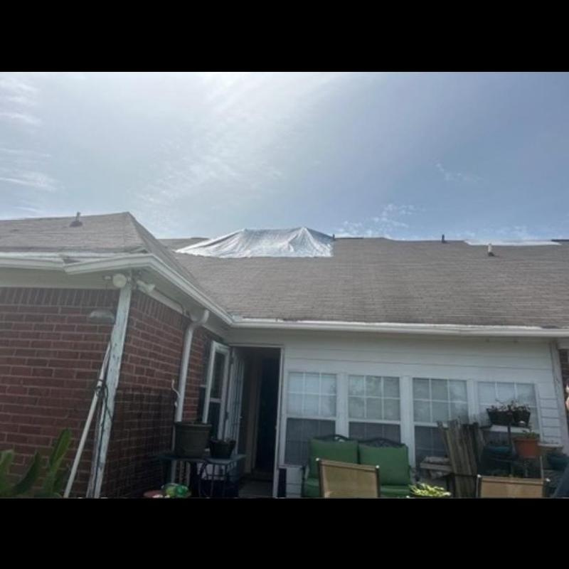 Roof tarp covering storm-damaged shingles on residential roof