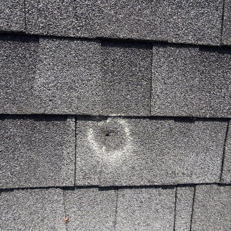 Asphalt shingle with puncture damage marked for repair