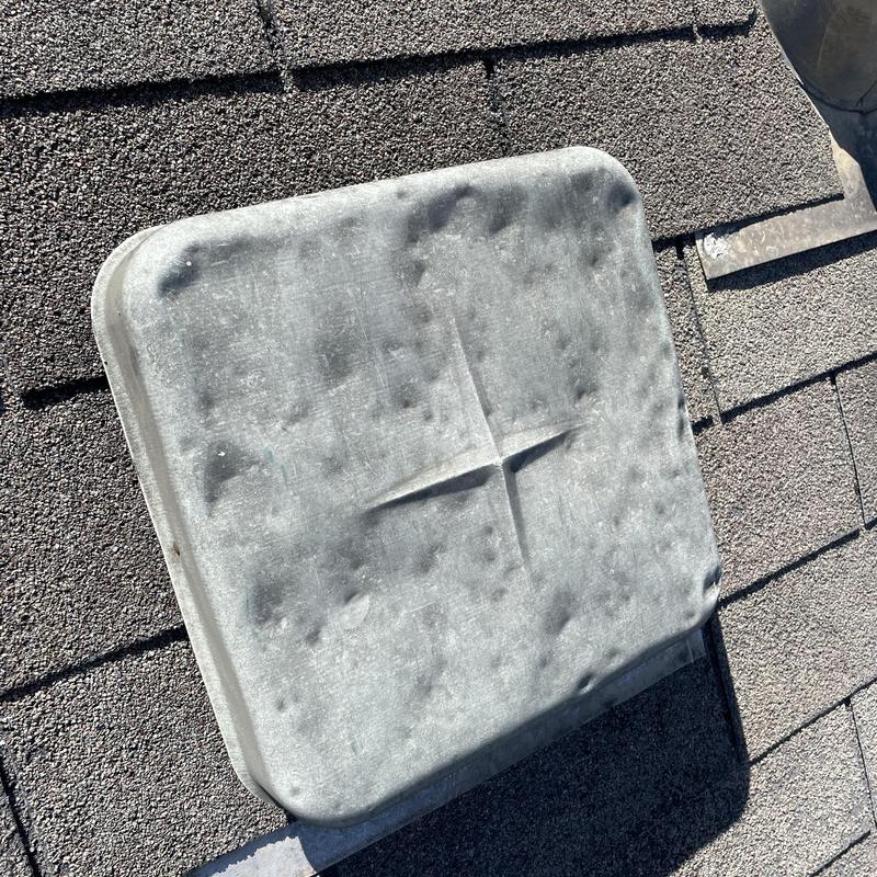 Roof vent cover with hail and wind damage on shingles Roof vent cover with hail and wind damage on shingles