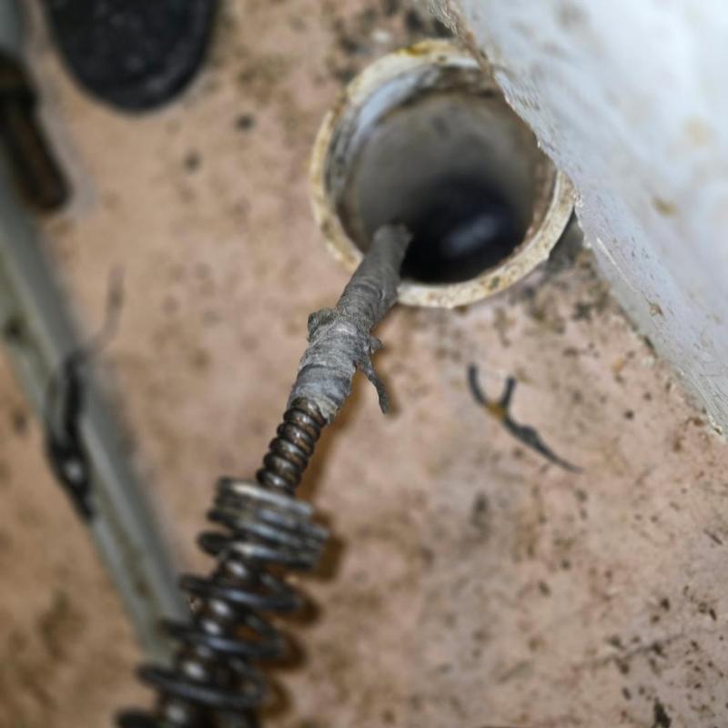 Main drain pipe with plumbing snake clearing blockage