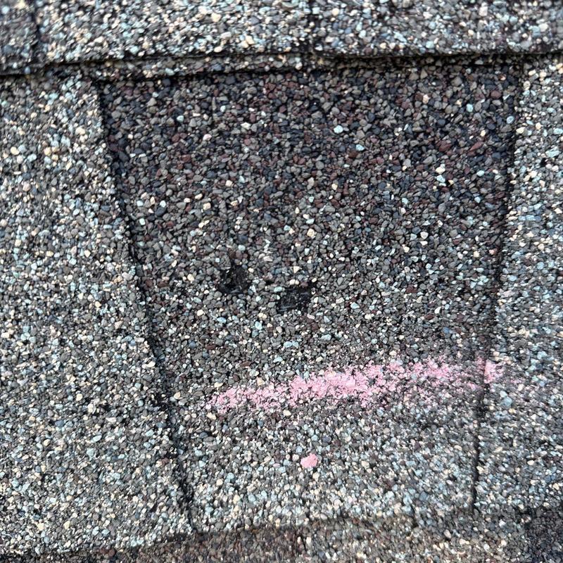 Asphalt shingle with marked hail damage on roof