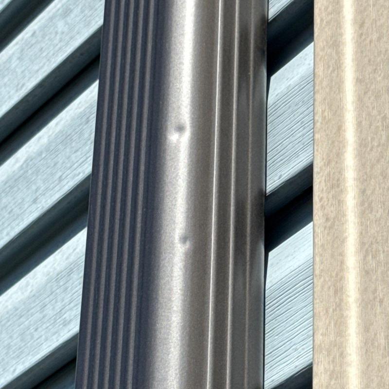 Metal gutter with hail damage dents on exterior wall