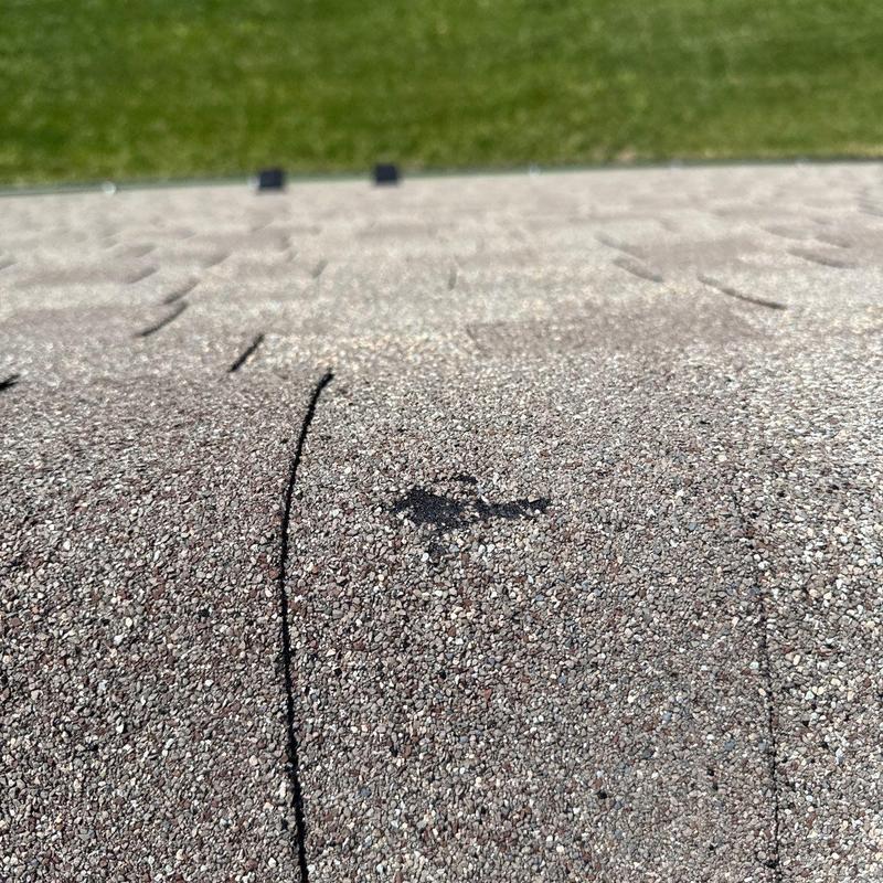 Asphalt shingle with hail damage close-up on roof surface