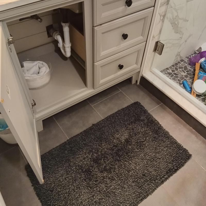 Bathroom sink drainage pipes under cabinet with rug Bathroom sink drainage pipes under cabinet with rug