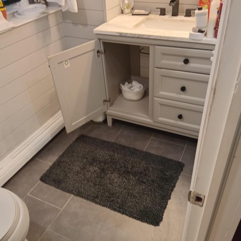 Bathroom sink cabinet with open door and plumbing access Bathroom sink cabinet with open door and plumbing access