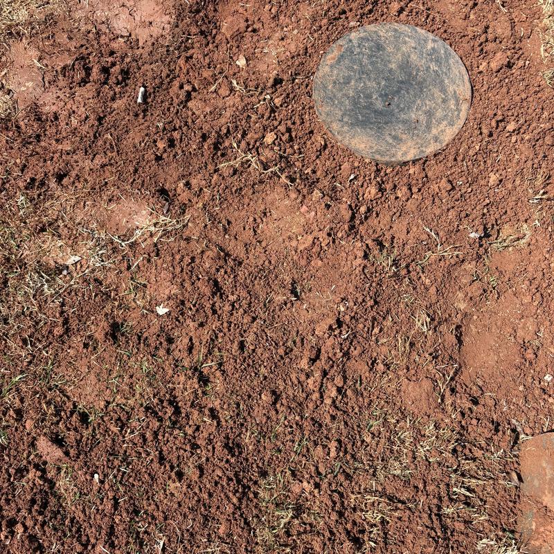 Water service line access cover in dirt yard