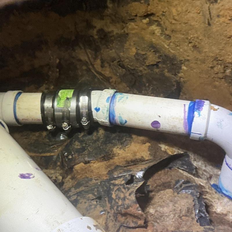 3-inch PVC pipe with metal clamps and fittings underground