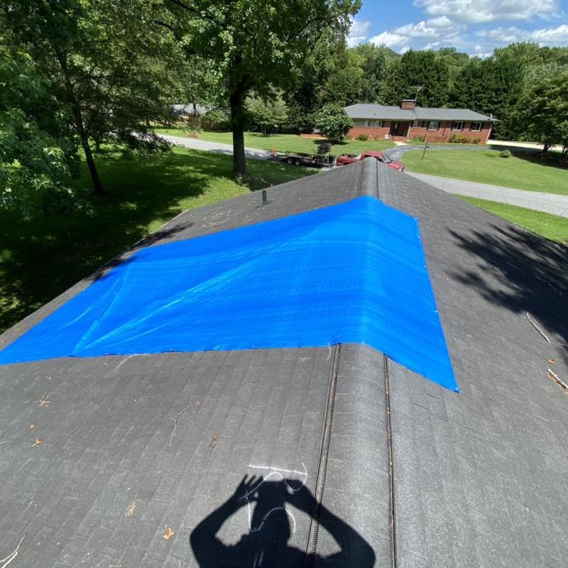 Roof tarp covering damaged shingle section on house roof Roof tarp covering damaged shingle section on house roof