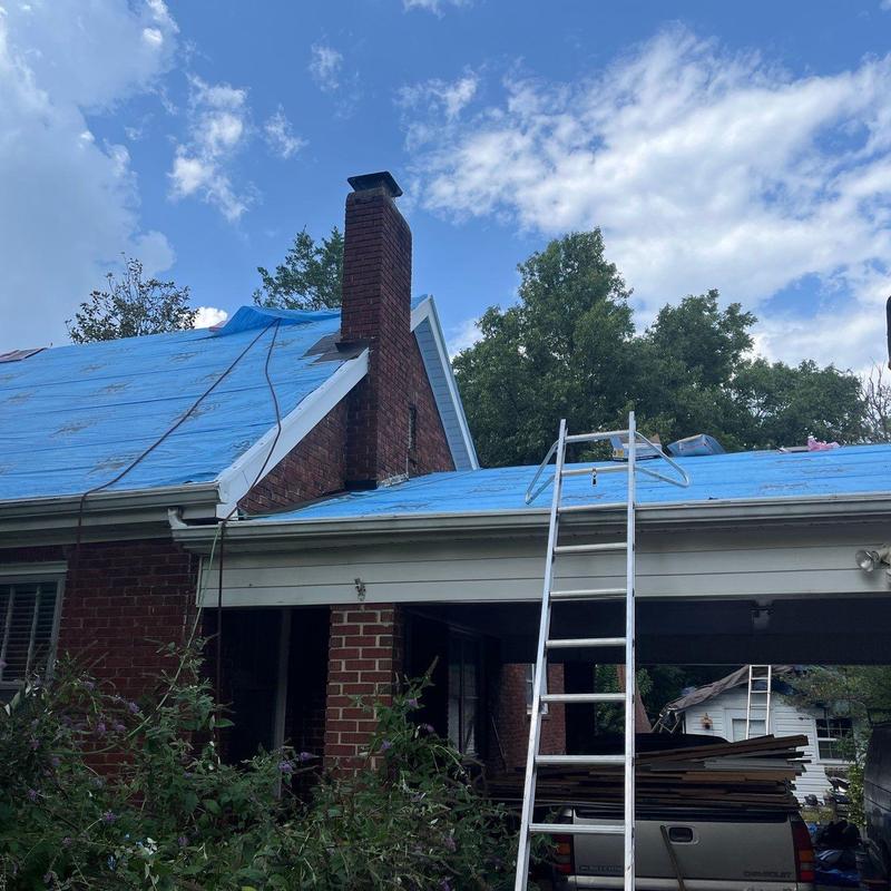 Roof underlayment installation with ladder on brick home