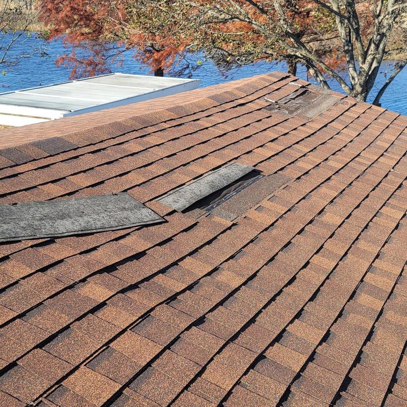 Asphalt shingle roof with missing and damaged shingles