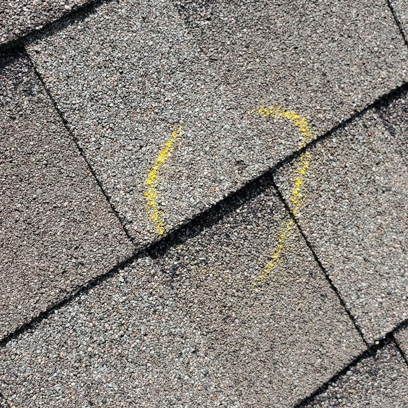 Asphalt shingle roof with hail damage marked in yellow