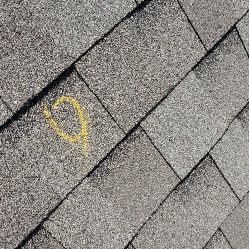 Roof shingles with yellow chalk marking hail damage