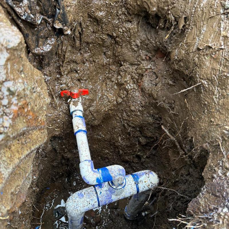 Main water line with valve in muddy excavation site
