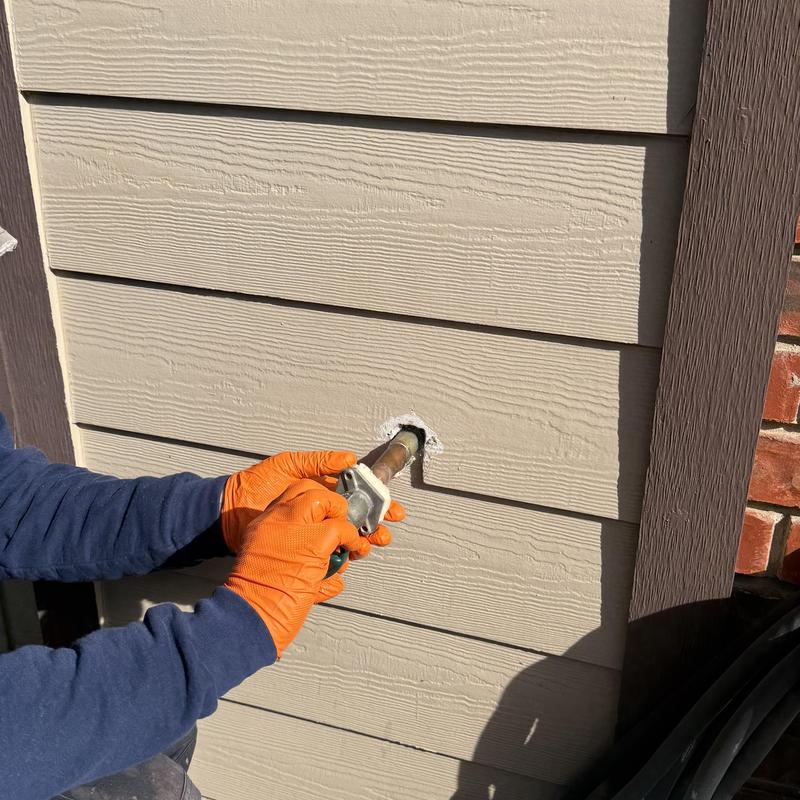 Hose bib replacement on exterior wall with orange gloves